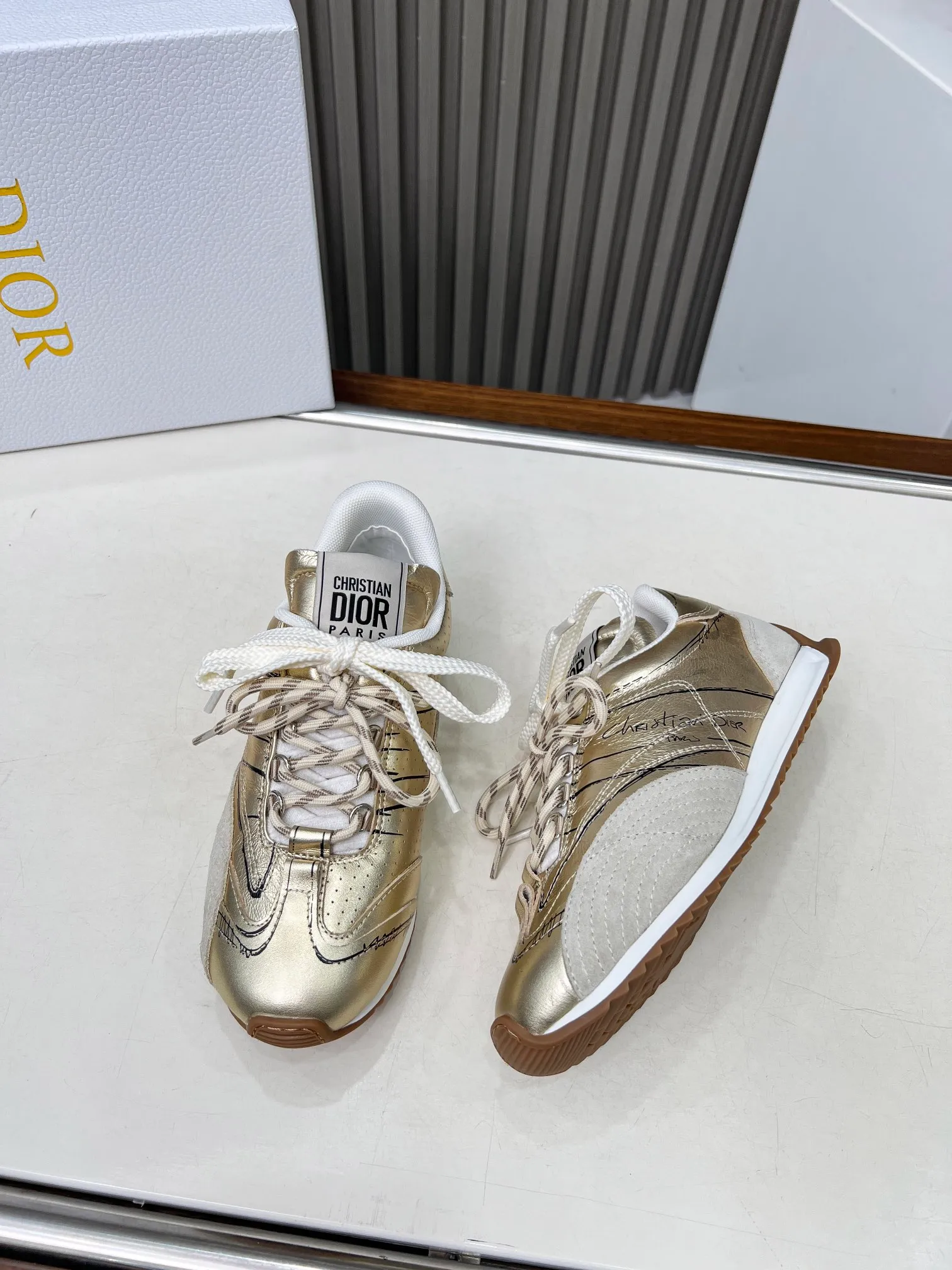 👟👟Ex-factory price 560👟👟 This D-Sketch sneaker is a new product of the 2025 spring and summer ready-to-wear series, highlighting the classic retro aesthetics. Crafted from gold-tone crinkled sheepskin and gold-toned laminated calfskin, it features a printed logo inspired by the shoe's production stages, as well as beige suede calfskin panels and double laces. Hand-written Christian Dior Paris signature on the side, Christian Dior Paris signature panels and plaques on the heel and tongue. Paired with two-tone slim rubber soles, they add a touch of couture to any casual look. Code number: 35~45 Color: black white gold silver